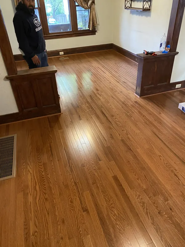 Red oak floor running through a room with deep stained trim and a bay window