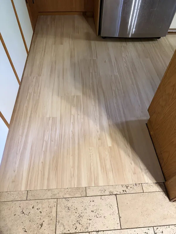 New plank flooring meeting an existing travertine floor at a clean transition